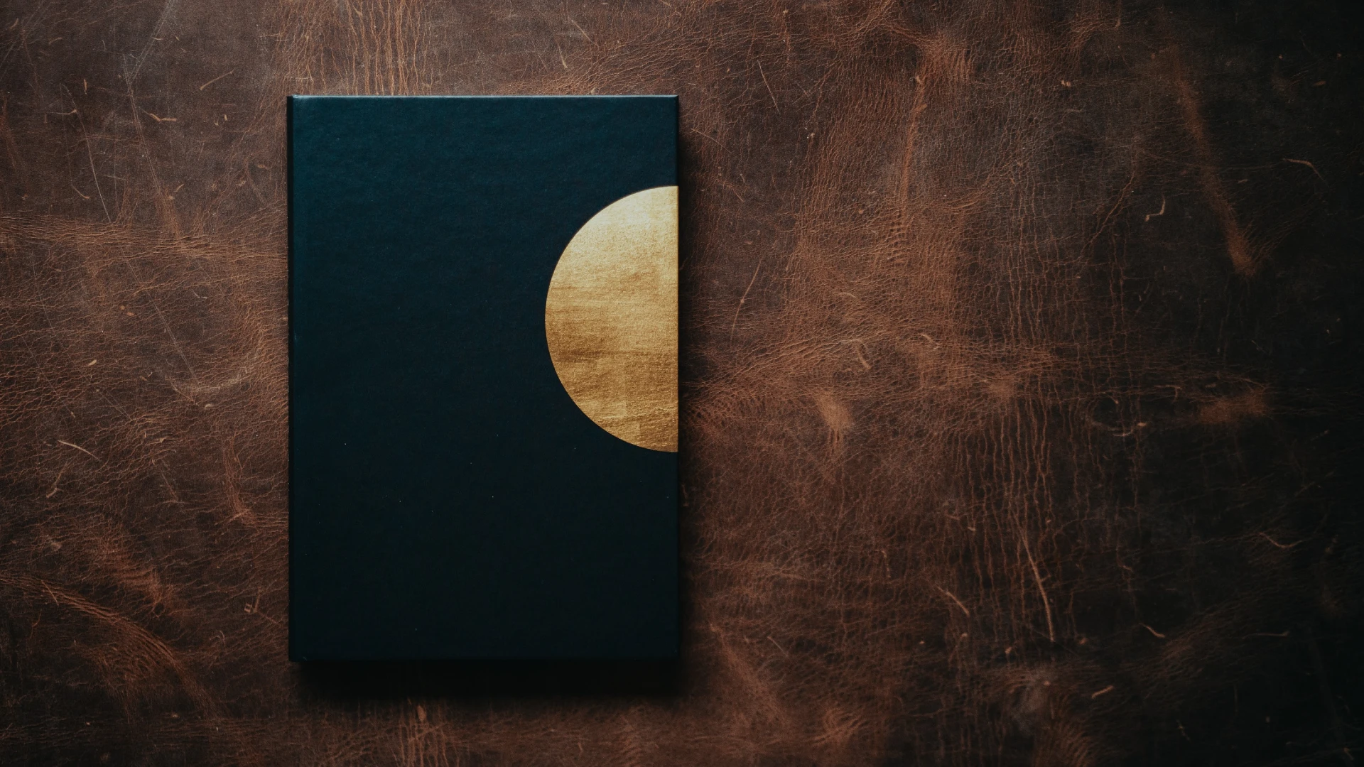 A book on Ikigai covered with a dark envelope with semicircular disk that reminds the sun over a dark brown wood table